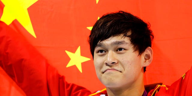 In this Saturday, Aug. 4, 2012 file photo, China's Sun Yang holds his national flag after winning the gold medal in the men's 1500-meter freestyle swimming final at the Aquatics Centre in the Olympic Park during the 2012 Summer Olympics in London. Chinese swimmer Sun Yang has been banned for eight years for breaking anti-doping rules and will miss the 2020 Tokyo Olympics.