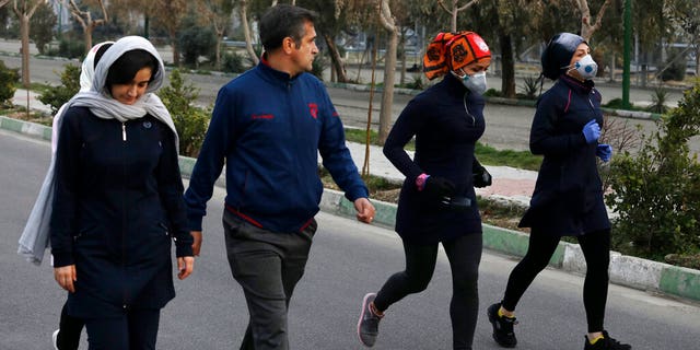 Two women jog with face masks on as others walk while enjoying their weekend afternoon at Pardisan Park in Tehran, Iran, Friday, Feb. 28, 2020. Iranians in Tehran on Friday found time to enjoy their weekend, even as authorities canceled Friday prayers and closed universities, schools and parliament over fears about the new coronavirus.