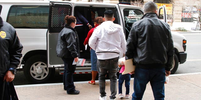 A father, in white, holds the hand of his daughter as they and other asylum seekers leave court under guard after some of them learned that they won't have to return to Mexico in light of a major federal court ruling against the Trump administration on Friday, Feb. 28, 2020, in El Paso, Texas.