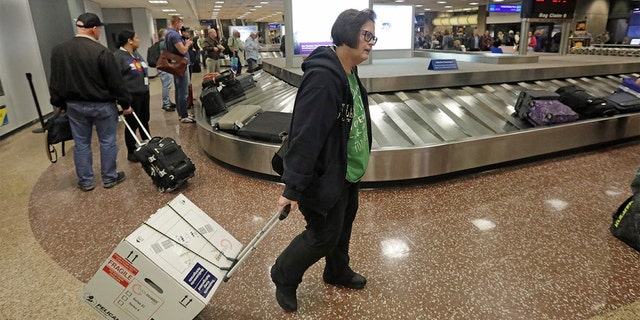 Ann Lovell carrying her box of prescriptions after returning to Salt Lake City International Airport following her visit to Tijuana, Mexico, last month. (AP Photo/Rick Bowmer, File)