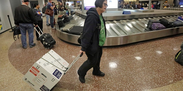 Ann Lovell carrying her box of prescriptions after returning to Salt Lake City International Airport following her visit to Tijuana, Mexico, last month. (AP Photo/Rick Bowmer, File)