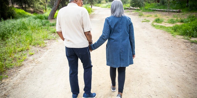 A senior couple walk on a road.