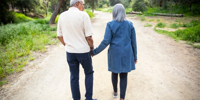 A senior couple walk on a road.