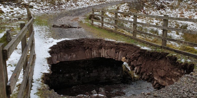 A large hole can be seen after part of a bridge collapsed at a national park in Wales on Wednesday.