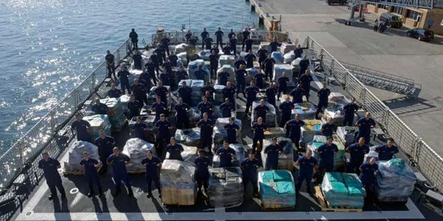Members of the Coast Guard cutter Hamilton stand next to more than two dozens tons of cocaine.