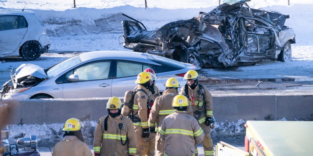 Emergency personnel stand next to demolished cars following a massive pileup involving numerous vehicles on the south shore of Montreal in La Prairie, Quebec, Wednesday, Feb. 19, 2020.