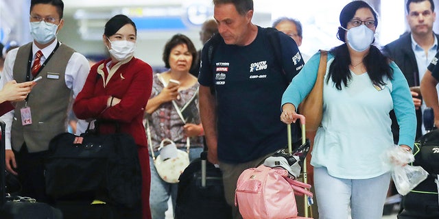 Coronavirus' frightening profile: Who is more likely to die from COVID-19? | USNN World News Members of a flight crew from Cathay Pacific Airways (L), wearing protective masks, stand in the international terminal after arriving on a flight from Hong Kong at Los Angeles International Airport (LAX) on February 28, 2020.