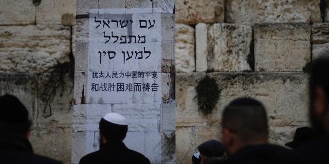 Judeus rezam no Muro das Lamentações, o local mais sagrado onde os judeus podem rezar na Cidade Velha de Jerusalém, domingo, 16 de fevereiro de 2020. Enquanto as preocupações com a disseminação do coronavírus aumentam, os fiéis judeus realizaram uma sessão de oração domingo no Muro das Lamentações em busca do divino intervenção para ajudar a evitar doenças contagiosas. O pôster em hebraico e chinês diz: "O povo de Israel ora pela China". (Foto AP / Ariel Schalit)