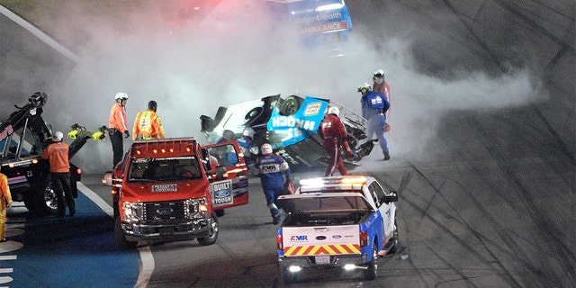Track personnel arriving to help Ryan Newman (6) after he flipped his car on the final lap in front of the grandstands during NASCAR Daytona 500. (AP Photo/Phelan M. Ebenhack)