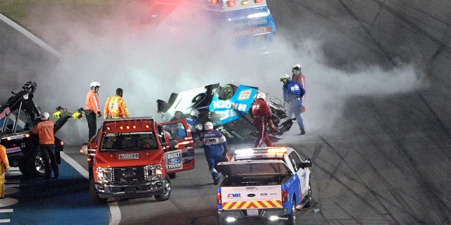 Track personnel arriving to help Ryan Newman (6) after he flipped his car on the final lap in front of the grandstands during NASCAR Daytona 500. (AP Photo/Phelan M. Ebenhack)