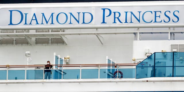 A passenger talks on a mobile phone on the quarantined Diamond Princess cruise ship anchored at a port in Yokohama, near Tokyo, Thursday, Feb. 20, 2020. (AP Photo/Eugene Hoshiko)