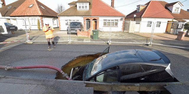 A view of a Toyota car in a sinkhole which appeared overnight in the aftermath of Storm Ciara, in Brentwood, England, Monday, Feb. 10, 2020.