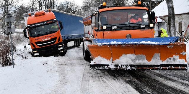 A snowplow pulls a truck stranded along a snow-covered road in the village of Naklerov, Czech Republic, Wednesday, Feb. 5, 2020.