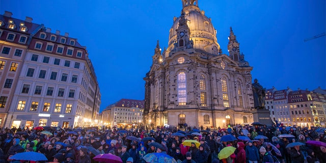 People gather in front of the Frauenkirche for the opening event of the human chain on the occasion of the 75th anniversary of the destruction of Dresden in the Second World War, in Dresden, Germany, Thursday. (Jens B'ttner/dpa via AP)