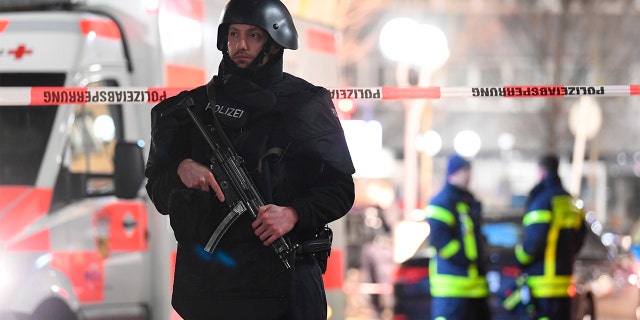 A police officer stands guard near the scene in front of a restaurant after a shooting in central Hanau, Germany Thursday, Feb. 20, 2020. Eight people were killed in shootings in the German city of Hanau on Wednesday evening, authorities said. (Boris Roessler/dpa via AP)