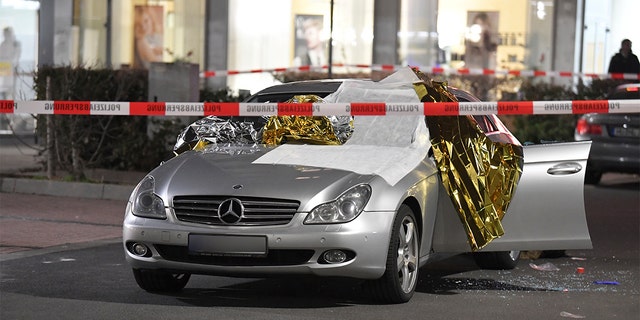 A car that was damaged in a shooting is covered in thermo foil is parked in front of a bar at the scene in Hanau, Germany early Thursday, Feb. 20, 2020. German police say several people were shot to death in the city of Hanau on Wednesday evening. (Boris Roessler/dpa via AP)