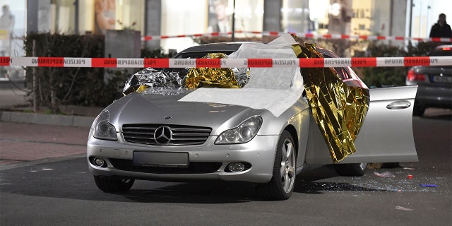 A car that was damaged in a shooting is covered in thermo foil is parked in front of a bar at the scene in Hanau, Germany early Thursday, Feb. 20, 2020. German police say several people were shot to death in the city of Hanau on Wednesday evening. (Boris Roessler/dpa via AP)