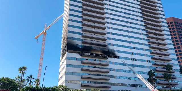 A Los Angele Fire Department ladder stands at the side of a 25-story high-rise apartment building where a fire broke out on a sixth-floor balcony and sent choking smoke billowing through the upper levels in West Los Angeles Wednesday, Jan. 29, 2020. (AP Photo/Stafanie Dazio)