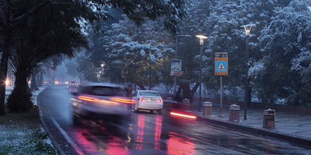Fresh snow falls while motorists drive through Abu Nawas street in central Baghdad, Iraq, Tuesday, Feb. 11, 2020.