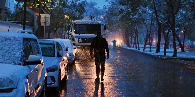 A man walks on a road while it snows in Baghdad, Iraq, Tuesday, Feb. 11, 2020.