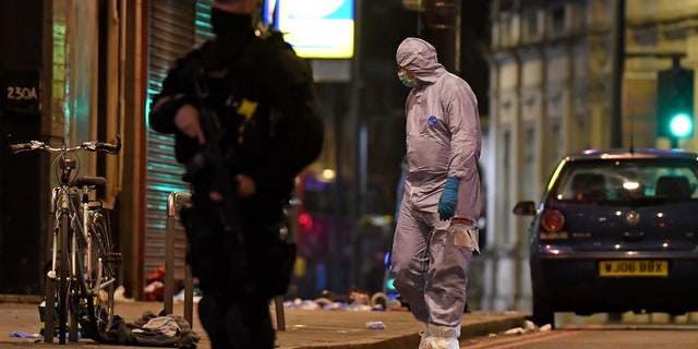 A police forensic officer looks around near the scene after a stabbing incident in Streatham London, England, Sunday, Feb. 2, 2020.