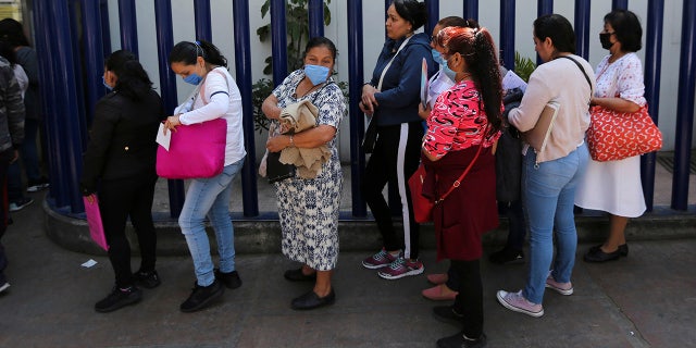 Women wear masks over their mouths as a precaution against the spread of the new coronavirus as they wait to enter as visitors the national hospital that specializes in respiratory diseases, the INER, in Mexico City, Friday, Feb. 28, 2020. Mexico's assistant health secretary announced Friday that the country now has confirmed cases of the COVID-19 virus. (AP Photo/Fernando Llano)