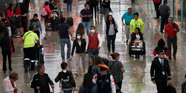 A couple wears protective masks as a precaution against the spread of the new coronavirus at the airport in Mexico City, Friday, Feb. 28, 2020. Mexico assistant health secretary announced Friday that the country now has confirmed cases of the COVID-19 virus. (AP Photo/Marco Ugarte)
