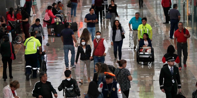 A couple wears protective masks as a precaution against the spread of the new coronavirus at the airport in Mexico City, Friday, Feb. 28, 2020. Mexico assistant health secretary announced Friday that the country now has confirmed cases of the COVID-19 virus. (AP Photo/Marco Ugarte)