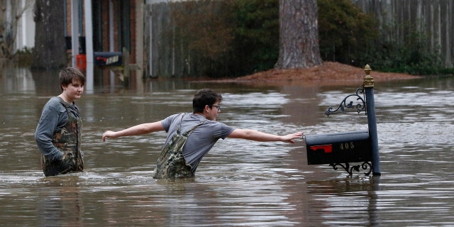 Blaine Henderson, right, reaches to tag a mailbox as Pearl River as he and his friend Jonah Valdez, both 12, play in the floodwaters of this northeast Jackson, Miss., neighborhood, Sunday, Feb. 16, 2020.