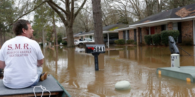 Chris Sharp studies the water damage from the Pearl River that floods his neighborhood in Jackson, Miss., Sunday, Feb. 16, 2020.