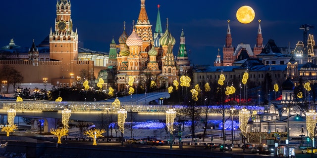 A full moon lights up the sky above the waterfront of the Moscow Kremlin.