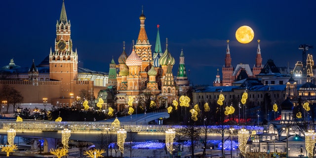 A full moon lights up the sky above the waterfront of the Moscow Kremlin.