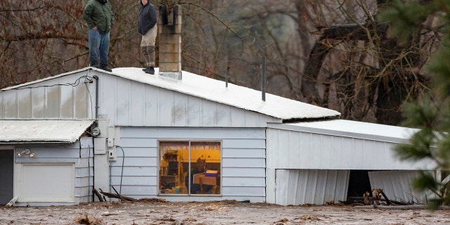Feb. 6, 2020: Nate Fuller and Archie Morrow await rescue on the roof of a home in Thorn Hollow outside of Adams, Ore.
