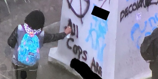 A person can be seen vandalizing a war memorial during a demonstration in downtown Portland, Ore. on Saturday.