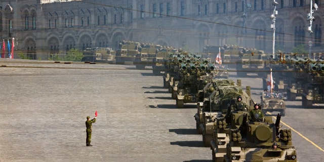 Russian soldiers stand near a convoy of rocket launchers in military parade rehearsal on Red Square, Moscow.