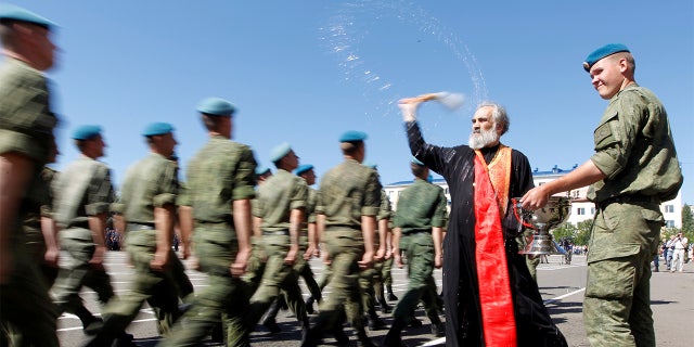 An Orthodox priest blesses Russian paratroopers marching during 2017 Paratroopers' Day celebrations, the annual holiday of Russian Airborne Troops, at their military unit in the southern city of Stavropol, Russia. 