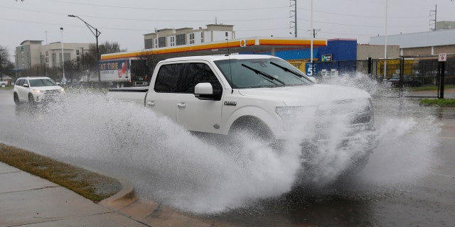A vehicle sprays water as rain falls in downtown Jackson, Miss., Tuesday, Feb. 11, 2020, making for cascades of splashed water as traffic drives through.