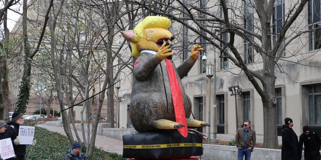 Anti-Stone protesters stand by a giant, blow-up rat version of President Trump.