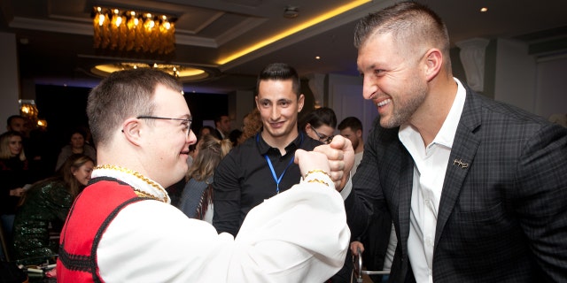 Tim Tebow fist bumps a guest at the "Night to Shine" in Albania.