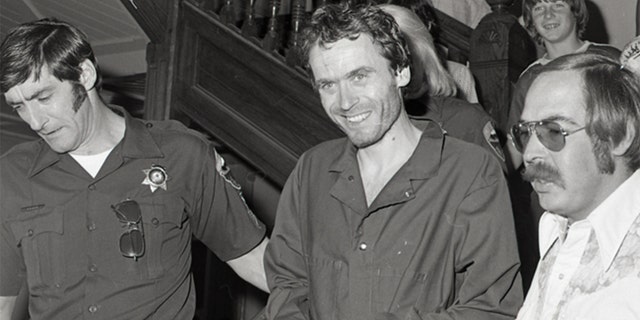 In this 1977 photo, serial killer Ted Bundy is escorted out of court in Pitkin County, Colo.  (Glenwood Springs Post Independent via AP)
