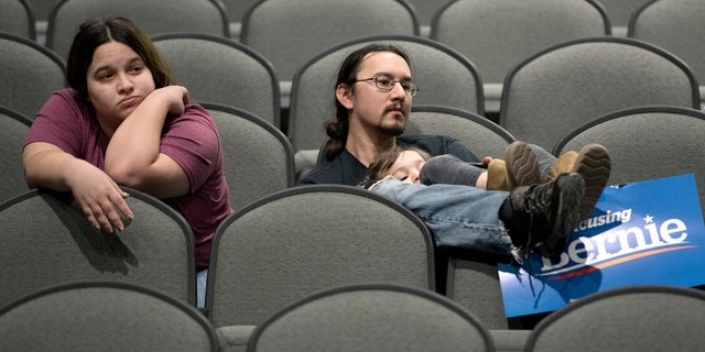 Jeff Lopez holds his son, Tristan, 4, as they and Jeff's wife, Jessika, sit in an area for Bernie Sanders supporters during the Woodbury County Third Precinct Democratic caucus, Monday, Feb. 3, 2020, at West High School in Sioux City, Iowa. Iowans across the state attended Democratic and Republican caucuses Monday. (Tim Hynds/Sioux City Journal via AP)