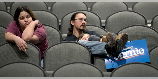 Jeff Lopez holds his son, Tristan, 4, as they and Jeff's wife, Jessika, sit in an area for Bernie Sanders supporters during the Woodbury County Third Precinct Democratic caucus, Monday, Feb. 3, 2020, at West High School in Sioux City, Iowa. Iowans across the state attended Democratic and Republican caucuses Monday. (Tim Hynds/Sioux City Journal via AP)