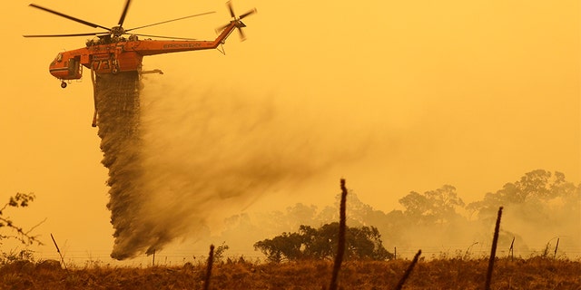 A helicopter drops water on a fire near Bumbalong, south of the Australian capital of Canberra, on Feb. 1, 2020.