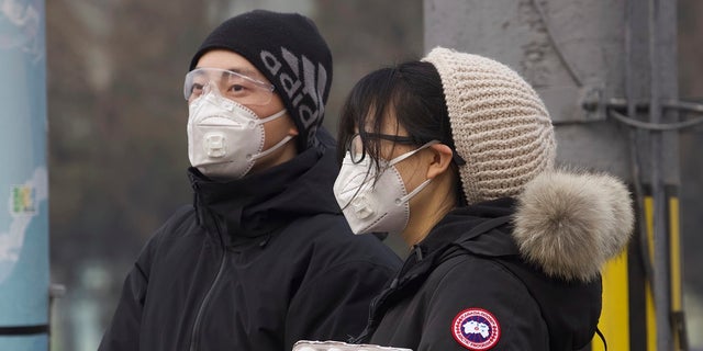 Residents wearing masks wait at a traffic light in Beijing earlier this month. Los Angeles area leaders relayed fears of coronavirus-related hate crimes this week. (AP Photo/Ng Han Guan)
