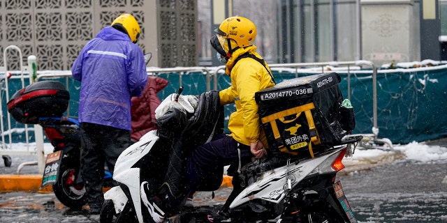 A food delivery man on his motor bicycle passes by an entrance of residential community on February 14, 2020 in Beijing, China.