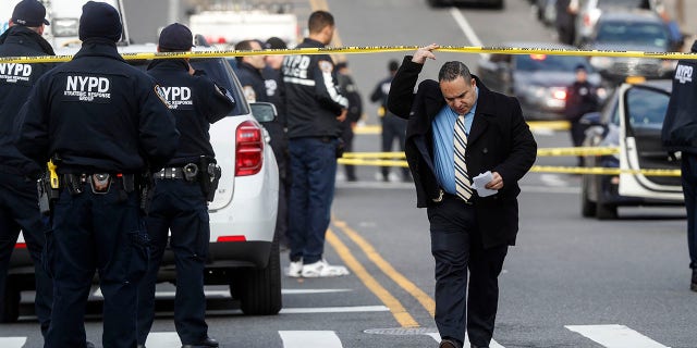 New York City police officers work the scene of a police-involved shooting outside the 41st precinct Sunday in the Bronx. (AP Photo/John Minchillo)