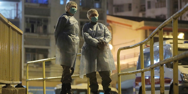 People wearing protective suits stand near the Cheung Hong Estate, a public housing estate, during the evacuation of residents in Hong Kong on Tuesday. (AP)