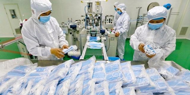 In this Friday, Feb. 7, 2020, photo, workers pack surgical masks at a factory in Suining city in southwest China's Sichuan province.