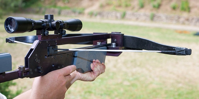 Man holding a scoped crossbow.