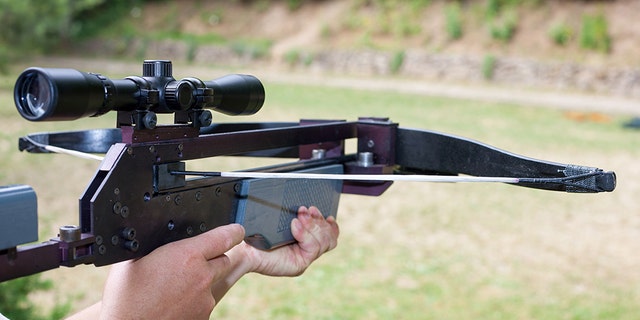 Man holding a scoped crossbow.